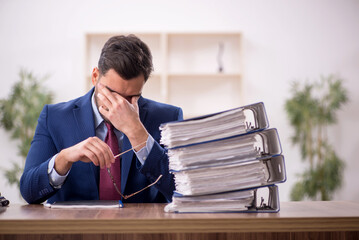 Obraz premium Young male employee and too much work in the office