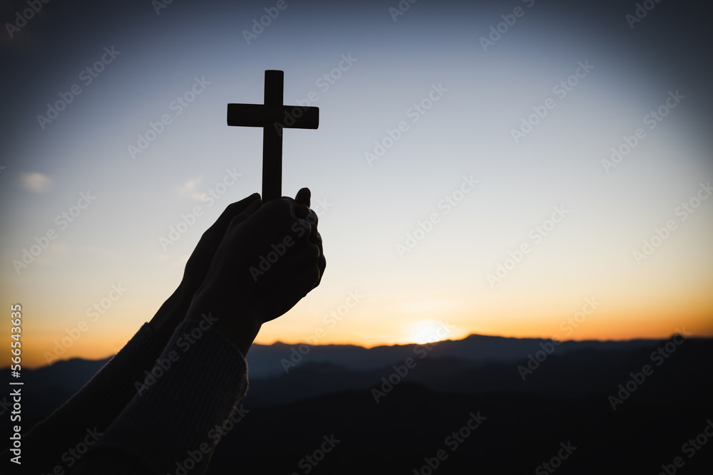 Wall mural Silhouette of christian woman hand praying, woman holding a crucifix praying, spirituality and religion, woman praying to god. Christianity concept.