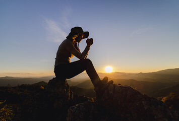 Silhouette of  man rise hand up on top of mountain and sunset sky abstract background. Freedom and...