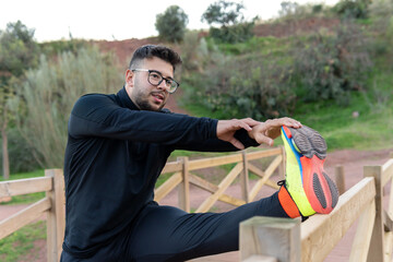 Athletic boy stretching on a bridge in the field before playing sports.