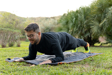 Young man exercising on the grass of a park to take care of his physique