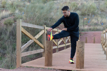 Young athlete stretching before starting to practice sports in the countryside, on the outskirts of the city.