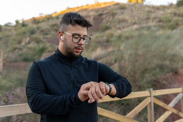 Athletic boy checking his heart rate on his smart watch after playing sports in the field.
