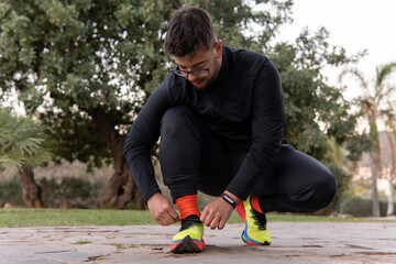 Young athlete in a park tying the laces of her tennis shoes before starting to play sports.