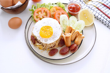 Fried rice and hot dogs, cooked fried egg, Chinese sausage and ketchup on a white background.