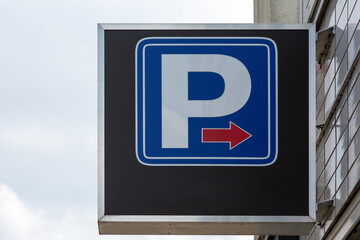 Ein blaues Schild mit dem Symbol  "P" für Parken und einem roten Pfeil nach rechts