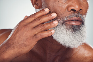 Hand, beard and face with a senior black man grooming in studio on a gray background for beauty or skincare. Skin, hygiene and cosmetics with a mature male indoor to promote facial hair maintenance