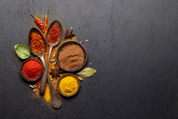 Various spices in bowls and spoons on stone table
