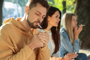 People smoking cigarettes outdoors on sunny day