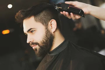 Fotobehang Kapsalon Professional hairdresser working with bearded client in barbershop  © New Africa