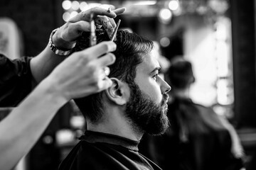 Professional hairdresser working with client in barbershop. Black and white effect