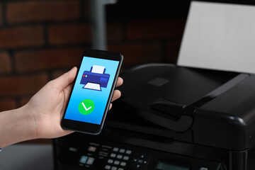Man using printer management application on mobile phone indoors, closeup. Image on device screen.