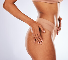Stretch marks, buttocks and underwear with a model black woman in studio on a gray background for body positivity. Cellulite, real and natural with a female posing in lingerie from the side