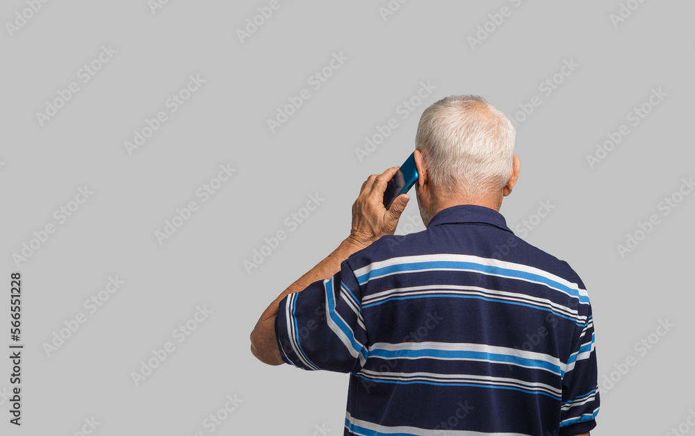 Poster back view of a senior man using a smartphone while standing on a gray background