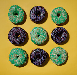 Multicolored donuts pattern on yellow background. Hard shadows. Flat lay. Top view