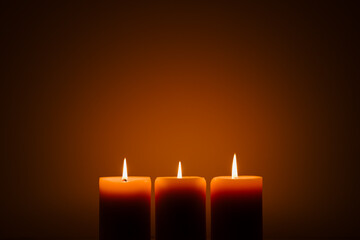 three burning candles in the dark. Memories and blessings