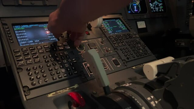 Captain handling the FMS computer inside a real jet cockpit during the pre-flight checks. Night light.