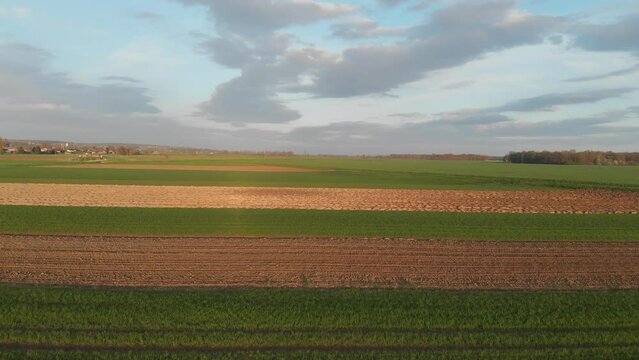 Aerial landscape view of cultivated agricultural fields on cloudy day in spring