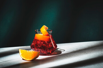 Fototapeta Boulevardier alcoholic cocktail with bourbon, vermouth, bitters, orange and ice. Dark green background, hard light and shadow pattern obraz