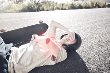 Pain, skateboarder and man with arm injury on road after fall, accident or exercise workout outdoors. Sports emergency, skating and crying male with bleeding elbow, painful wound and broken bones. © Jesse B/peopleimages.com