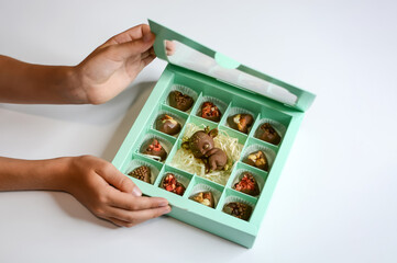 Chocolate cute fawn and candies with various fillings in a gift box. Child's hands hold a box of delicious chocolates	