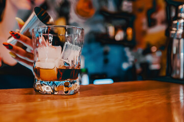 woman hand bartender making negroni cocktail. Negroni classic cocktail and gin short drink with sweet vermouth, red bitter liqueur in bar