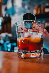woman hand bartender making negroni cocktail. Negroni classic cocktail and gin short drink with sweet vermouth, red bitter liqueur in bar