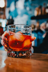woman hand bartender making negroni cocktail. Negroni classic cocktail and gin short drink with sweet vermouth, red bitter liqueur in bar