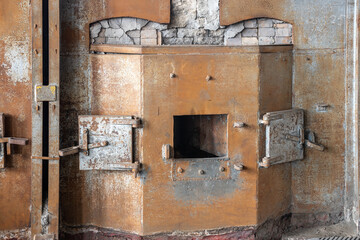 Fragment of melting furnace from the beginning of XX century. Opened doors of the hearth. Rusted and shabby cover of the furnace. Historical manufacture.