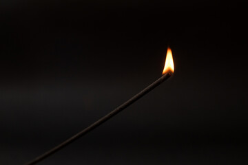 Fototapeta na wymiar Incense stick burning on a black background