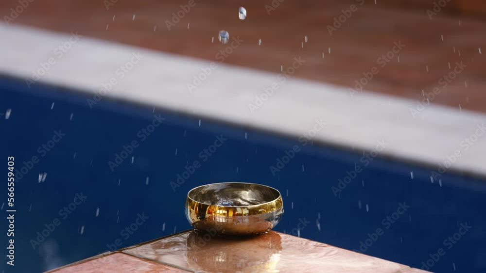 Poster water slashing in slow-motion in a small golden bowel at the edge of a pool