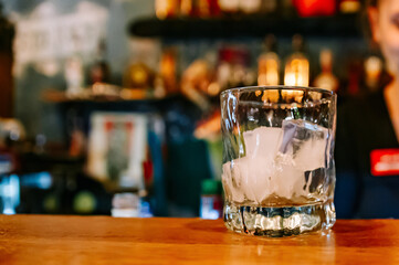 Ice cube in an empty glass on a bar counter in bar or pub