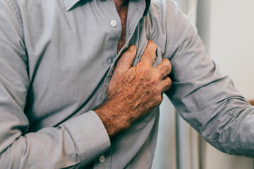 Senior man holding hand on chest and suffering from heart problem at home, Grandfather with heart...
