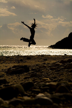 A woman jumps in the air on the beach, Crete, Greece.