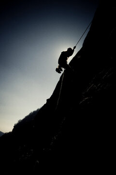 Silhouette of a young man rappelling down a cliff face in Cashiers Valley, North Carolina.