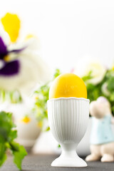 Easter interior, yellow Easter egg close-up on the background of flowers and cute rabbits