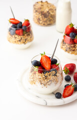 Homemade granola with almonds in a glass with yogurt, fresh strawberries and blueberries, delicious healthy breakfast