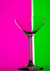 Cocktail party glass in neon colours. Close up photo on a colorful background. Modern elegant champagne glass.