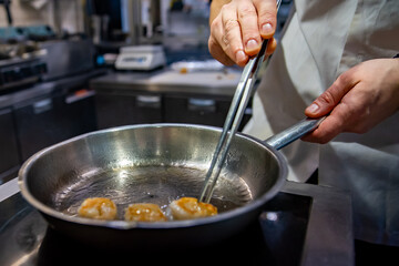 man chef cooking fried shrimp in frying pan on kitchen