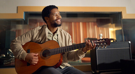 Musician, acoustic and man playing the guitar for music production or recording in studio. Artist, guitarist and African guy strumming the strings of a musical instrument for sound track performance. - Powered by Adobe