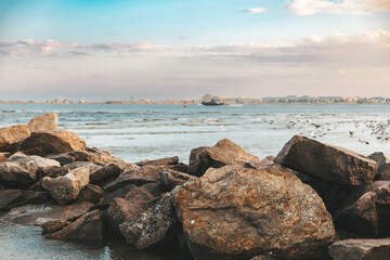 ship in the ocean ,blue sky at sunset,rocks foreground 