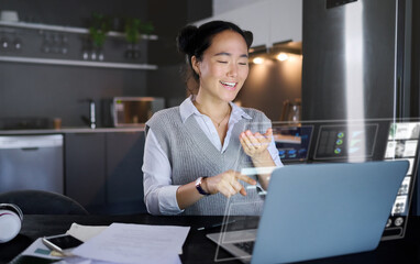 Laptop, futuristic hologram and woman in home kitchen laugh at funny meme. Freelancer, remote worker and Asian female pointing to computer with 3d, augmented reality or data graphs at night in house