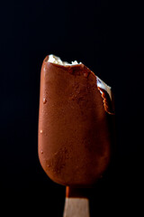 Ice cream on a stick on a black background. Ice cream bite. Bitten ice cream. Pieces of ice cream.
Bar of ice cream with chocolate coating on a black background.Glaze broke off ice cream