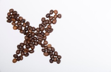 X is a capital letter of the English alphabet made up of natural roasted coffee beans that lie on a white background. Plenty of space to put text or pictures, top view and studio photography.