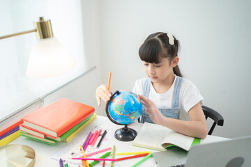 Portrait of happy young smiling child kid girl, Asian Thai woman searching at earth globe map model for travelling, people lifestyle.