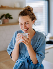 Young woman enjoying cup of coffee at morning, in her kitchen.