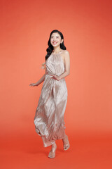 Beautiful woman in party dress posing on red background
