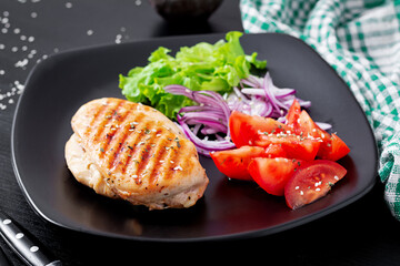 Grilled chicken breast. Fried chicken fillet and fresh vegetable salad of tomatoes, red onions and lettuce. Chicken meat with salad.