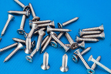 Tapping screws made of steel on blue or water color background, metal screw, iron screw, chrome screw, screws as a background, wood screw, concept industry. copy space for text.