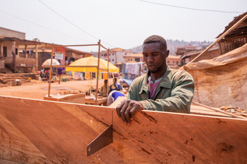 A carpenter cuts a board with a hand saw in his workshop in Africa